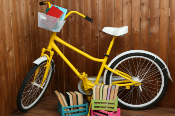 Books stacked in basket of yellow bike