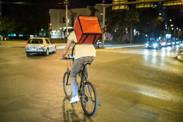 Food delivery bike rider on road at night