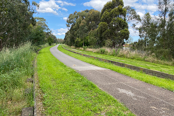 The Lower Prospect Canal cycleway. The edges of the canal are left visible to either side of the shared path and hint at the history of the corridor and its importance for NSW public health. (Image: Bicycle NSW)