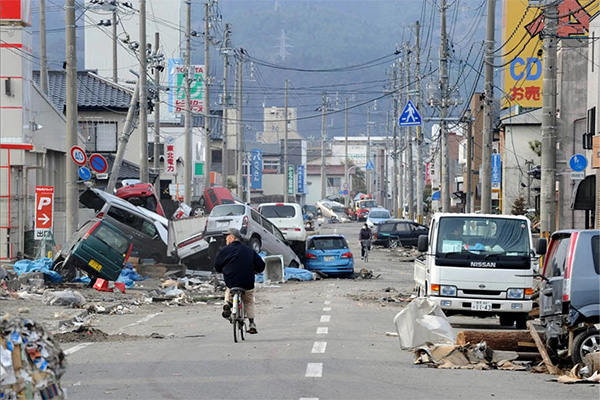 Bike riders navigate a devastated street in Japan after the 2011 tsunami (Image: National Post)